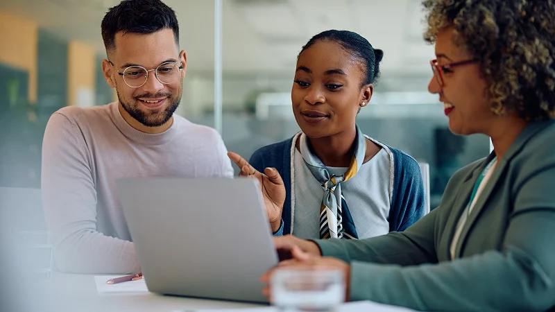 A professional discussing information on a laptop with a young couple.