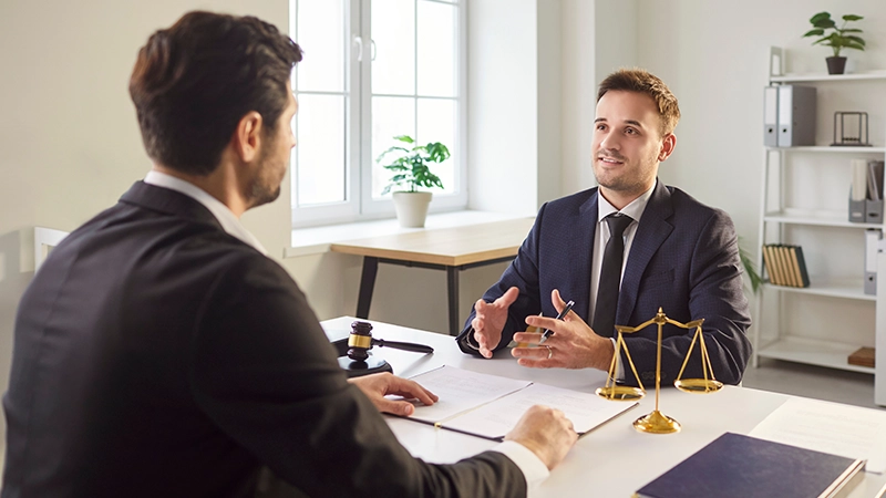 Confident lawyer in suit sitting at desk, discussing legal case with client in his office.